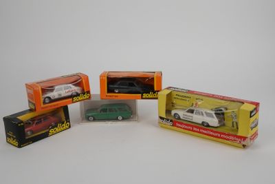 Quatre petites voitures dans leur boîte sont alignées sur une surface blanche