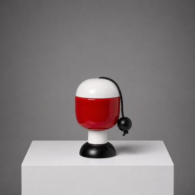 une lampe rouge et blanche posée sur un socle blanc