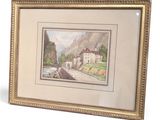 framed picture of a painting of a mountain village with a bridge in the foreground