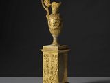 un vase en or posé sur un socle, sur fond noir