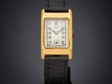 a gold plated wrist watch with a black leather strap