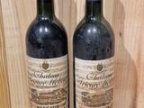 pair of two bottles of wine sitting on a wooden shelf