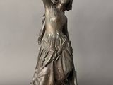 an antique bronze statue of a woman holding a bird in her hand