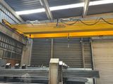 an overhead crane in a warehouse with a lot of steel bars