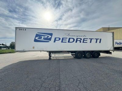 La semi-remorque est garée sur le parking, près d'un bâtiment.
