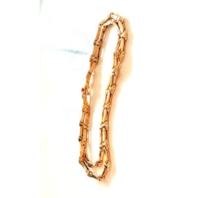 une photo d'un bracelet en or posé sur une surface blanche