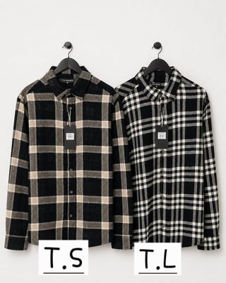 two men ' s shirts hanging on a hanger in front of a white wall