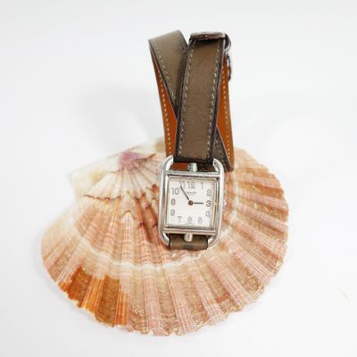 a watch sitting on top of a shell on a white surface