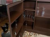 a small cabinet with wine glasses on it in a living room