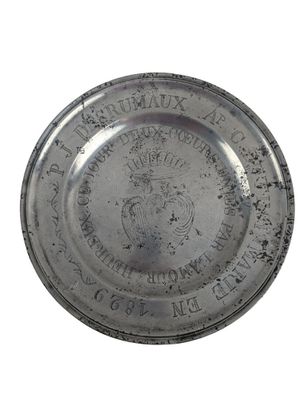 an old silver plate with a crown on it on a white background