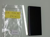 un téléphone portable noir à côté d'un autocollant jaune sur un mur blanc