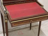 a small desk with a red top and gold trim