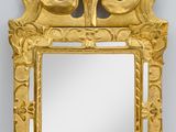 un miroir richement sculpté, avec un cadre doré, accroché à un mur blanc