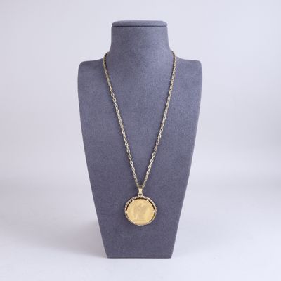 un collier composé d'une pièce d'or suspendue à une chaîne autour du cou d'un mannequin