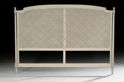 the headboard of a white bed with a rattan style frame