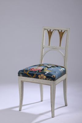 une image représentant une chaise blanche avec une assise bleue et un revêtement à motifs floraux