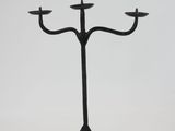 a black metal candelabra with three candles on a tripod stand