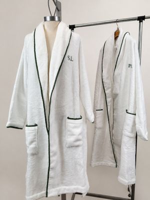 two white bathrobes hanging on a clothes rack next to a white wall