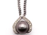 a close up of a black pearl and diamond pendant on a chain