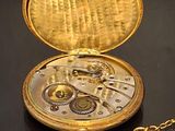 a gold pocket watch sitting on a table with a chain