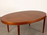 a large oval teak dining table with two leaves on the top