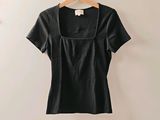 une chemise noire accrochée au mur à côté d'un cintre en bois