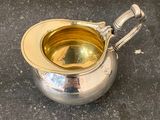 a silver sauce pot with a handle on a table