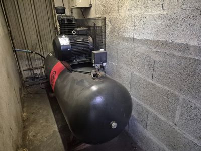 un réservoir muni d'une pompe, placé à côté d'un mur de briques