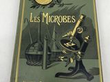 an old book with a microscope on it sitting on a table