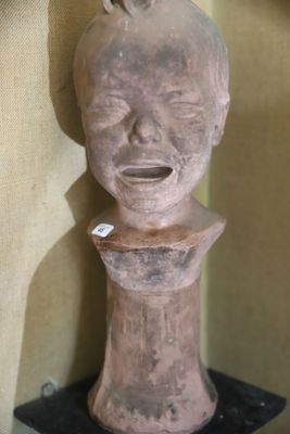 une sculpture en argile représentant un visage, posée sur un socle