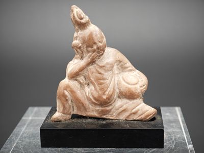 une statue représentant un homme assis sur un bloc de marbre