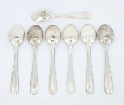 six cuillères et un repose-cuillère sur une surface blanche