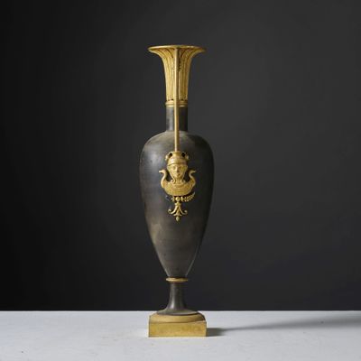 un vase noir et doré posé sur une table blanche