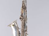 an old silver saxophone sitting on top of a white surface