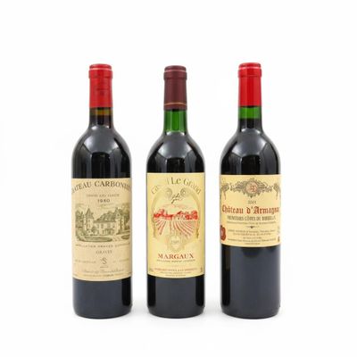 trois bouteilles de vin rouge sont posées côte à côte sur une surface blanche