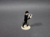 a figurine of a man holding a newspaper and a cane