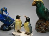 three figurines of birds that are sitting on a rock
