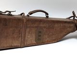 un étui en cuir marron orné d'une étiquette marron, posé sur une surface blanche