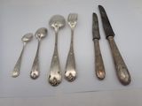 five spoons and a knife on a white table