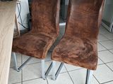 two brown leather chairs sitting next to each other on a tiled floor