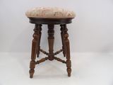 un vieux tabouret en bois dont l'assise est recouverte d'un tissu à motifs floraux