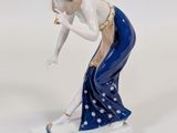 a figurine of a woman bending down to pick something