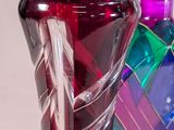 a person holding a colorful glass vase in their hand