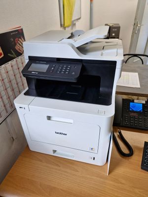 une imprimante posée sur un bureau, à côté d'un téléphone