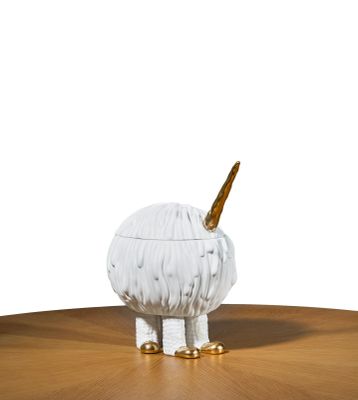 une figurine d'animal blanche et dorée posée sur une table en bois