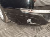a close up of a car ' s front bumper with a person standing in the background