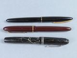 trois types de stylos différents sont alignés sur une surface blanche