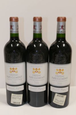 trois bouteilles de vin sont alignées sur une surface blanche