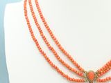 a close up of a mannequin wearing a necklace with orange beads