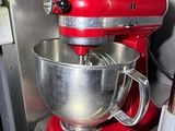 a red mixer sitting on a counter in a kitchen